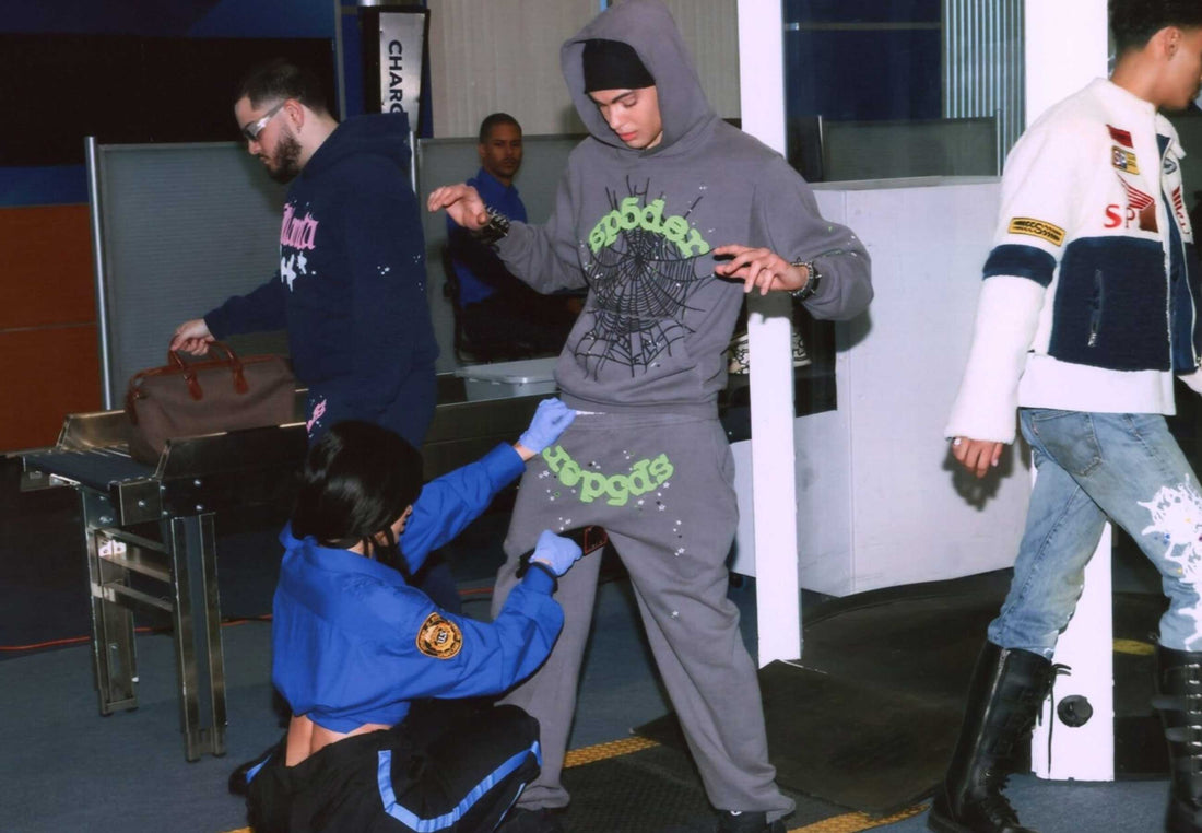 Image depicts 3 men walking through airport TSA security wearing Sp5der Worldwide Sweatsuits, featuring hoodies, sweats, and more.