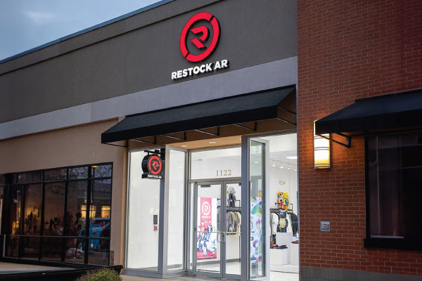 Image of the front of our Streetwear Fashion and Sneaker Storefront Called "Restock AR" in Rogers, AR. Image shows front of store with neon lit Restock AR Logo