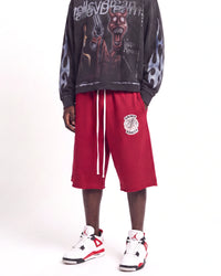 Saint Vanity Crimson Uniform Shorts red, waist-down front view on model showing the crest logo and drawcord