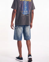 A model from the back wearing a faded black graphic t-shirt, blue denim shorts, and black low-top sneakers with white soles, set against a plain white studio background.