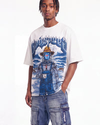 A model wearing a white graphic t-shirt featuring a blue and yellow 'Blindspot' character design, paired with blue denim cargo pants, against a plain white studio background.