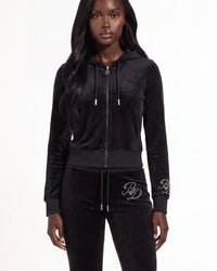 A model wearing a black velvet zip-up hoodie and matching black velvet sweatpants with white embroidered 'RP' logos on the cuffs and thigh, photographed against a plain white studio background.