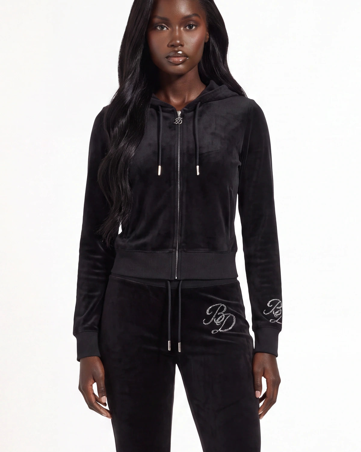 A model wearing a black velvet zip-up hoodie and matching black velvet sweatpants with white embroidered 'RP' logos on the cuffs and thigh, photographed against a plain white studio background.