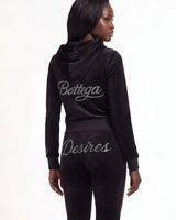 A model shown from the back wearing a black velour tracksuit with 'Bottega' and 'Desires' written in silver script across the back, against a plain white background.