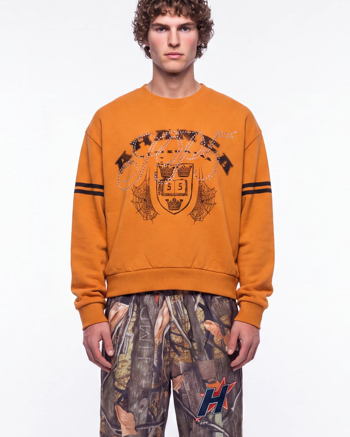 Sp5der Aranea Crewneck burnt orange, upper body front view on model showing the ARANEA crest graphic