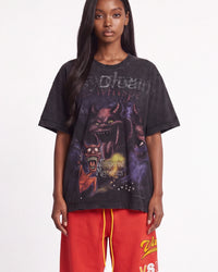 A model wearing a black acid-washed graphic t-shirt with a demonic design and red sweatpants, photographed against a plain white studio background.