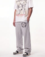 HMDD Chimstone Sweatpants grey, waist-down front view on model showing the circular emblem and HMDD type