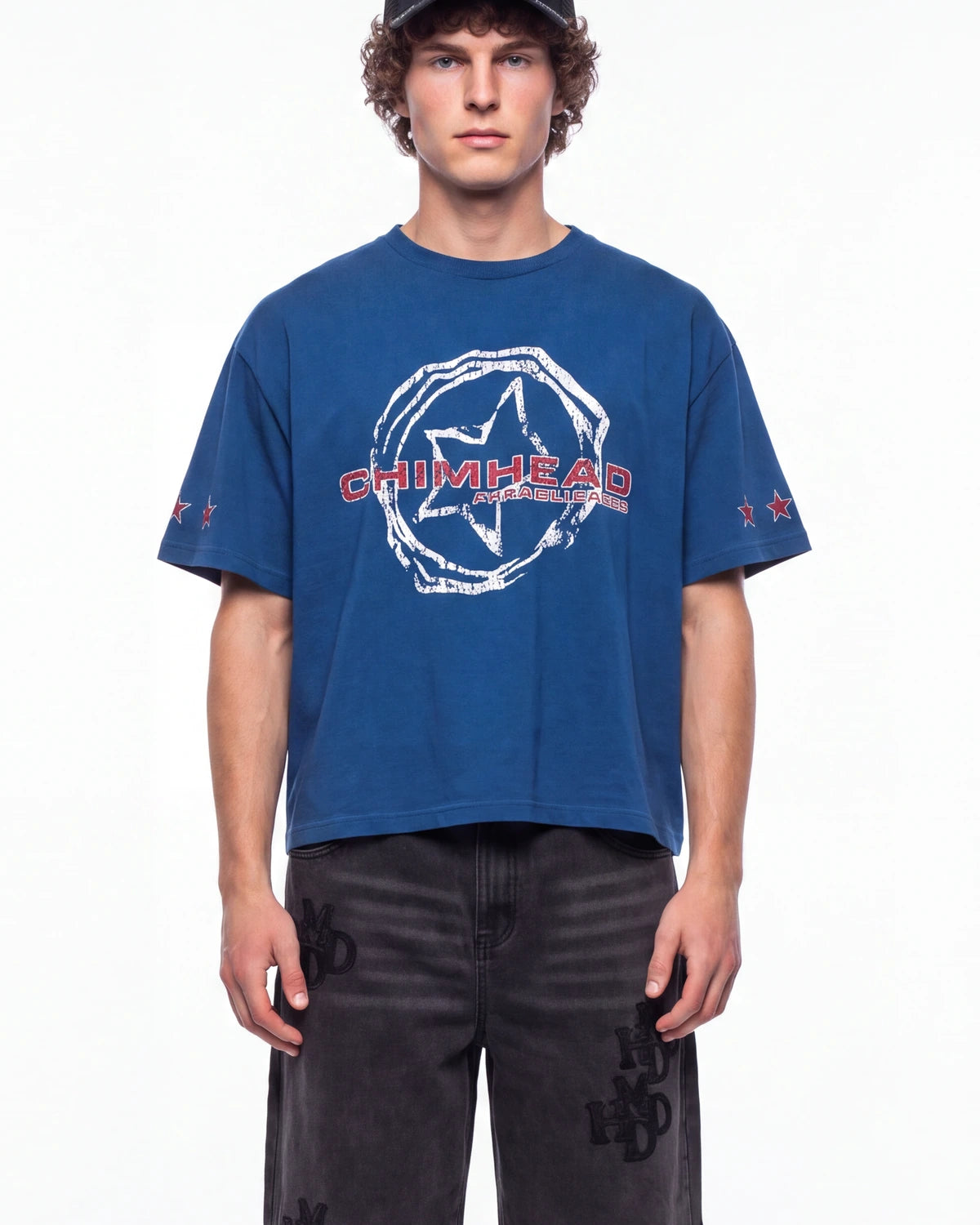 A man wearing a blue short-sleeve t-shirt with a white distressed graphic and red 'CHIMHEAD' text on the chest, paired with dark gray jeans, photographed against a plain white background.