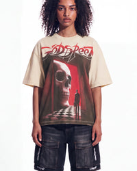 A model wearing a beige Godspeed t-shirt with a large red and black graphic print of a skull in a hallway, paired with dark cargo shorts, against a plain white background.
