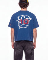 A person shown from the back wearing a blue cropped T-shirt with a large white outlined star graphic and red number 10 on the back, paired with dark jeans against a plain white studio background.
