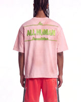 All Human Champagne Room Tee pink, upper body rear view on model showing the green ALL HUMAN lettering