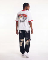 A model shown from the back wearing a white ringer t-shirt with red trim and a large graphic print on the back, paired with black graphic cargo pants and white sneakers, against a plain white studio background.