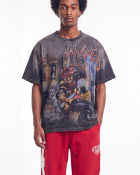 A model wearing a faded black graphic t-shirt with a detailed street art print and red sweatpants, photographed against a solid white background.