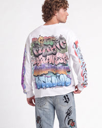 A model shown from the back wearing a white long-sleeve crewneck sweatshirt covered in colorful graffiti-style graphics, paired with light-wash jeans featuring graphic prints.