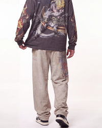 A person shown from the back wearing a dark gray long-sleeve graphic shirt with anime artwork and the text 'NILEYSEAN BEASTS' across the back, paired with light beige sweatpants and black-and-white sneakers, against a plain white studio background.