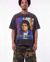 A man wearing a faded black graphic t-shirt featuring a colorful print of Michael Jackson with the text 'FAMOUS CELEBRITY', paired with green camouflage pants, against a plain white background.