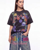A woman modeling a faded black graphic t-shirt with a colorful 'Valley Dream' print, paired with blue jeans featuring 'Valley Dreams Lives Forever' text and rhinestone embellishments, against a plain white background.