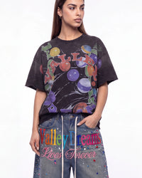 A woman modeling a faded black graphic t-shirt with a colorful 'Valley Dream' print, paired with blue jeans featuring 'Valley Dreams Lives Forever' text and rhinestone embellishments, against a plain white background.