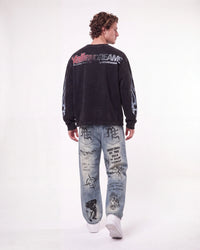 A man shown from the back wearing a black long-sleeve sweatshirt with 'Valley Dream' text on the back and light blue graphic jeans, against a plain white studio background.