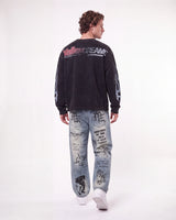 A man shown from the back wearing a black long-sleeve sweatshirt with 'Valley Dream' text on the back and light blue graphic jeans, against a plain white studio background.