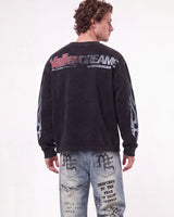 A man shown from the back wearing a faded black long-sleeve graphic sweatshirt with 'VallenDreams' printed across the upper back and distressed light-wash denim jeans with graphic prints.