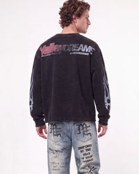 A man shown from the back wearing a faded black long-sleeve graphic sweatshirt with 'VallenDreams' printed across the upper back and distressed light-wash denim jeans with graphic prints.