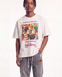 A man wearing an oversized off-white t-shirt with a colorful graphic print of faces and the text 'Deception Has Many Faces But There Is Only One Galaxy Sevens labels', paired with gray drawstring pants, against a plain white background.