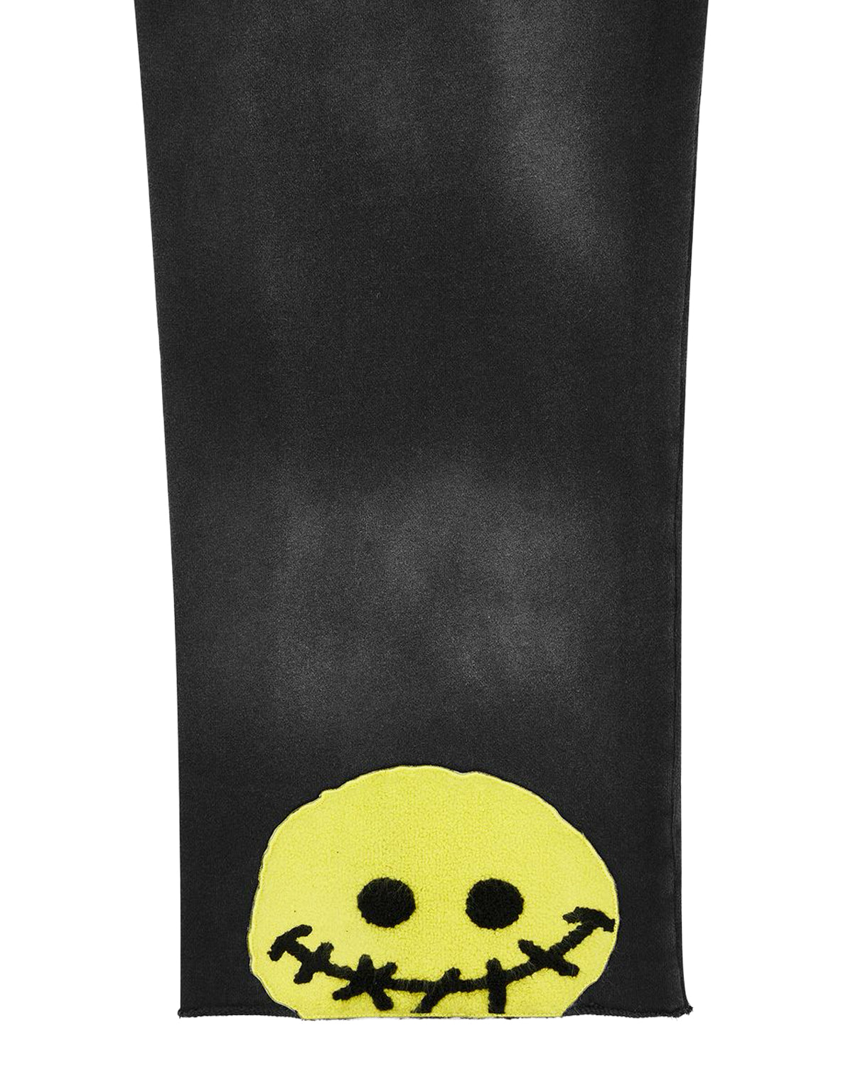 All Human Deli Set V2 Sweatsuit black wash, close-up of the stitched smiley patch on the pant leg