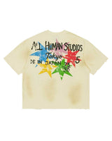 All Human Shinjuku Tee cream, back view showing the ALL HUMAN STUDIOS Tokyo lockup over a burst of multicolor stars