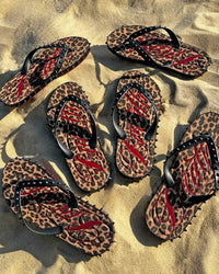 Bravest Studios Breathe Studded Flip Flops Leopard Print, worn on sand showing the leopard footbed and studded straps