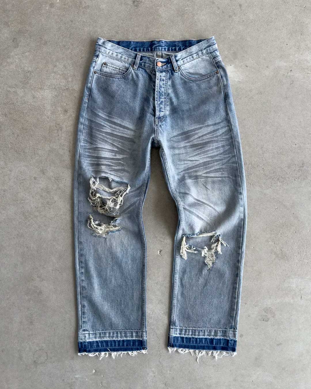 Bravest Studios Dirty Star Denim blue, flat-lay front view on concrete showing the baggy leg and knee blowouts