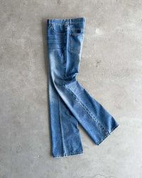 Bravest Studios Flare Denim Pants blue, flat-lay side view on concrete showing the boot-cut flare
