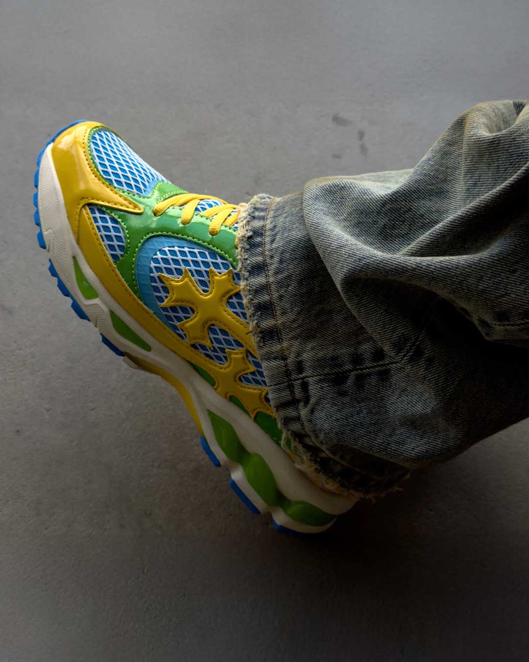 Bravest Studios Kross Kountry Runner Brazil, close-up worn on foot with washed denim showing the yellow cross applique and blue outsole