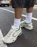 Bravest Studios Kross Kountry Runner Spring Green, worn on foot with white crew socks on asphalt, angled view