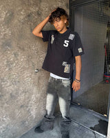 Bravest Studios Patch Polo black, worn by a model with baggy grey jeans, showing the boxy cropped fit
