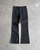Bravest Studios Raw Flare Denim black, flat-lay back view on concrete showing the flare from the knee
