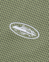 Corteiz HMP Classic Tank Top olive, close-up of the embroidered white Alcatraz Island oval on the waffle knit