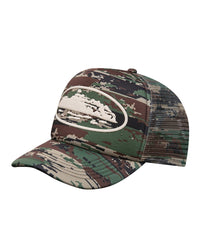 Corteiz Island Puff Print Trucker Hat digi camo, foam-front mesh-back trucker cap with raised white puff-print Alcatraz Island graphic, three-quarter front view
