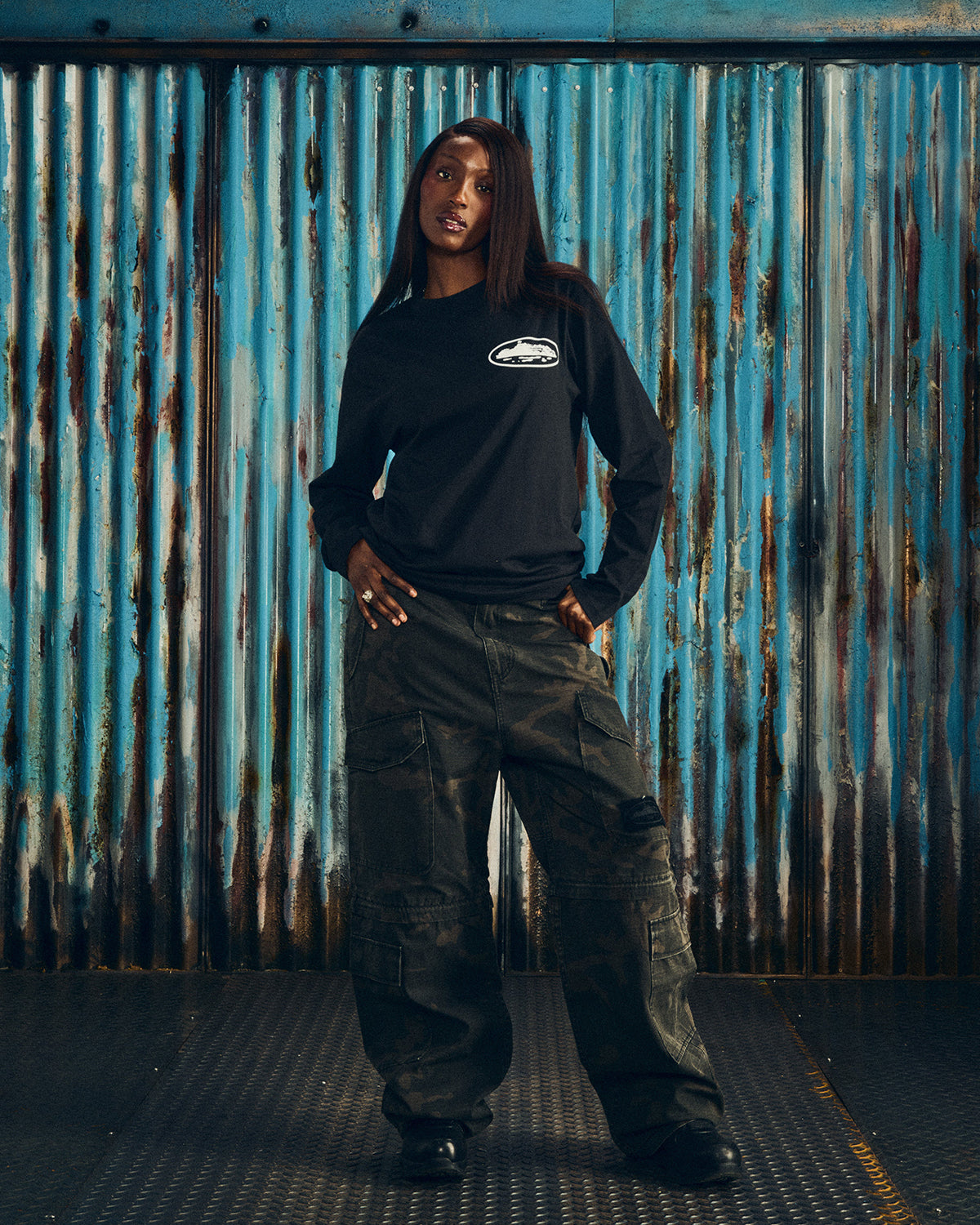 Corteiz OG Island LS Tee black, worn by a model with cargo pants, front view showing the small white chest island graphic