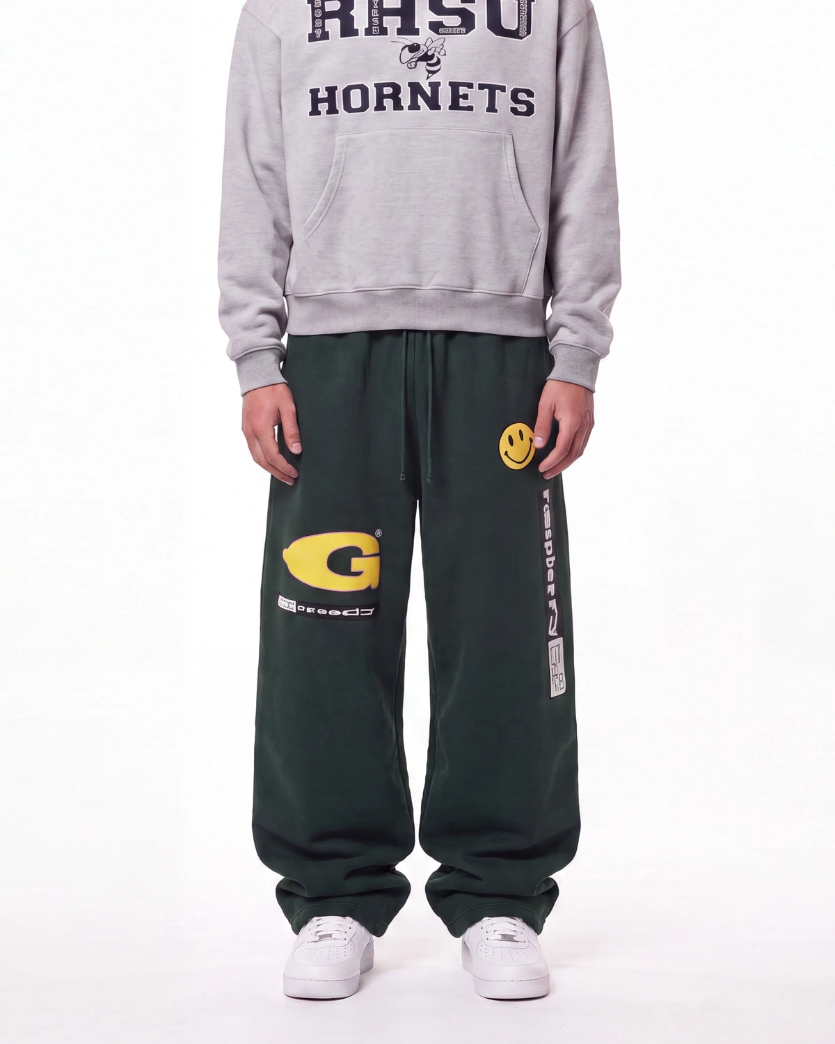 A person wearing dark green sweatpants with a yellow 'G' logo and white sneakers, paired with a gray hoodie featuring 'RHSU HORNETS' text, shown against a plain white background.