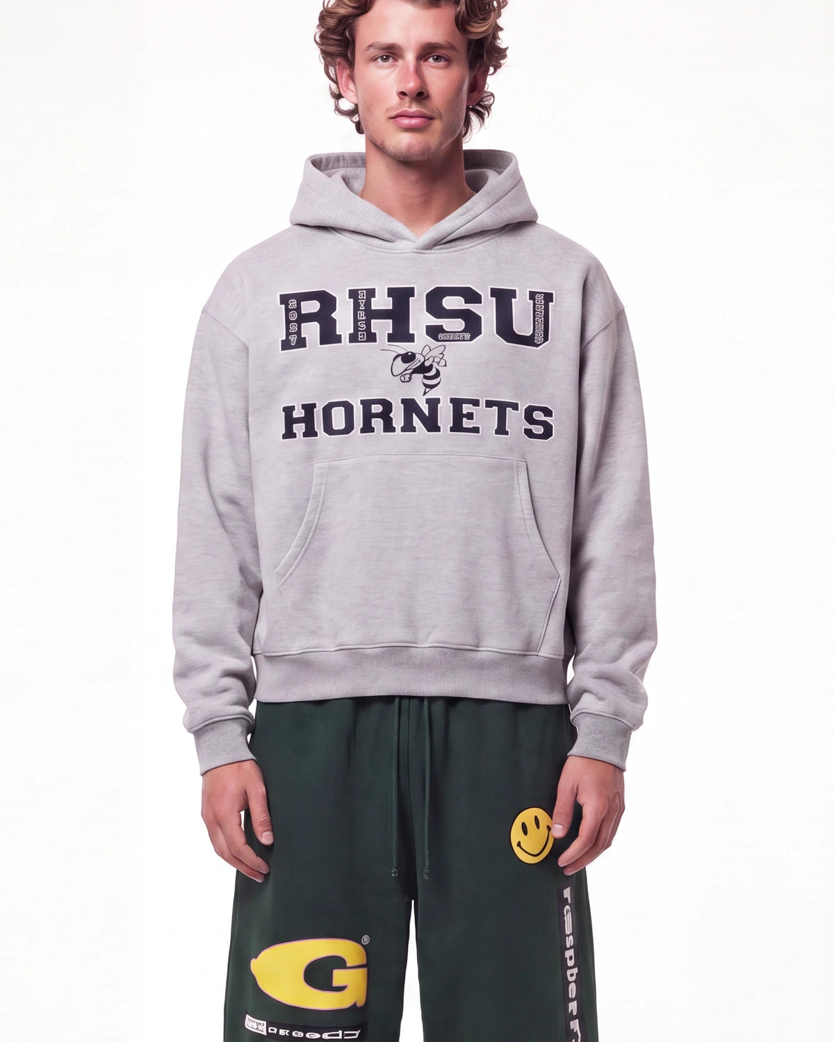 A male model wearing a light gray pullover hoodie with 'RHSU HORNETS' printed in navy blue on the front, paired with dark green sweatpants, against a plain white studio background.