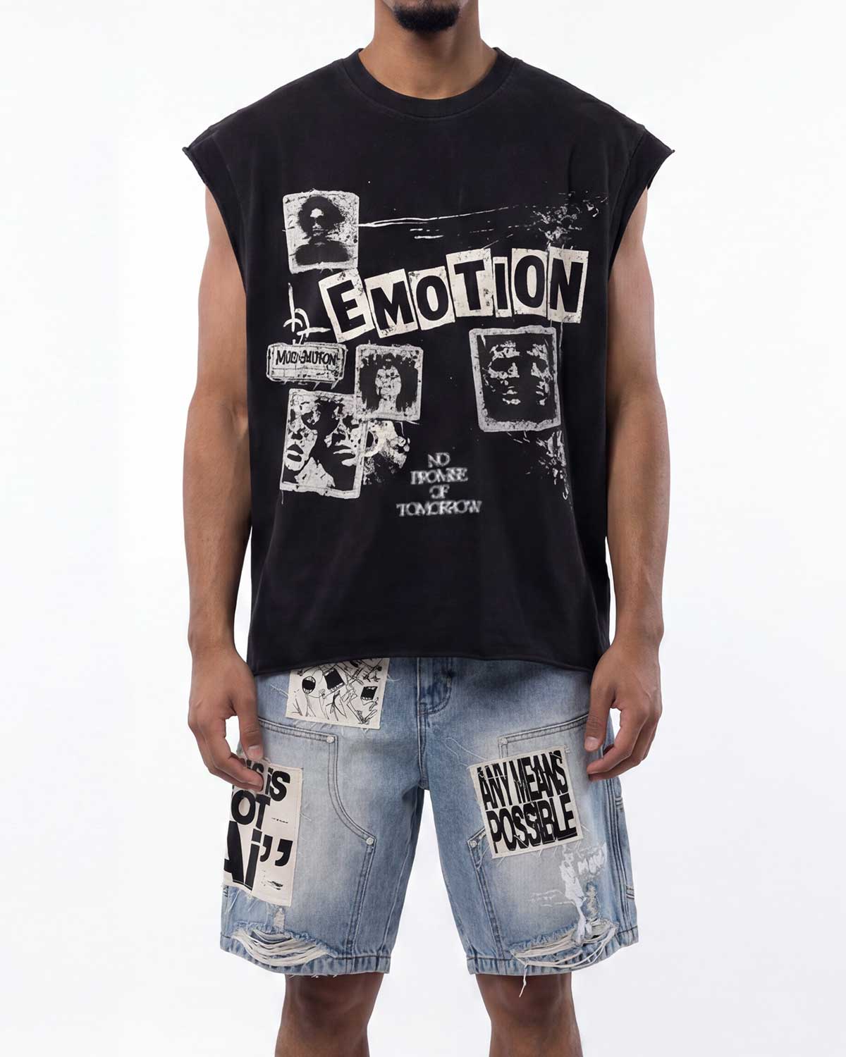 A man wearing a black sleeveless graphic t-shirt with white distressed text and images, paired with light blue denim shorts featuring ripped details and patches.