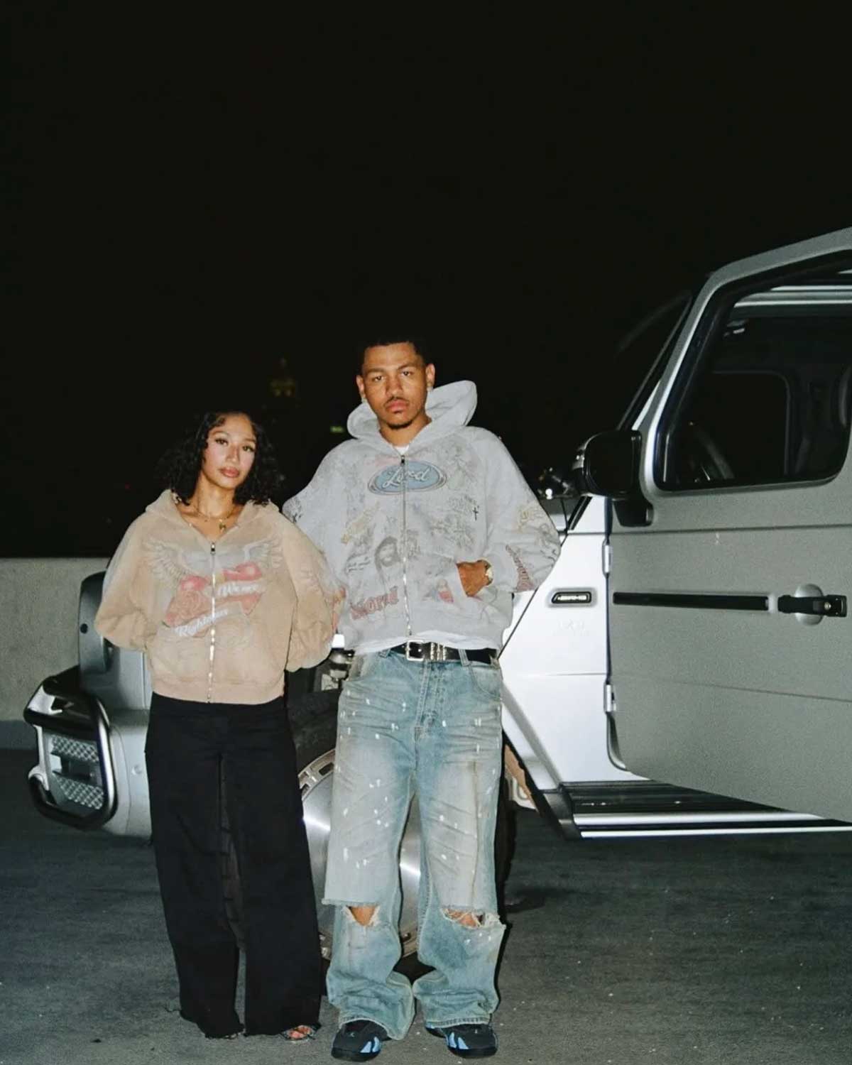 Two models standing beside a car wearing Righteous Jesus My Lord grey zip up hoodie