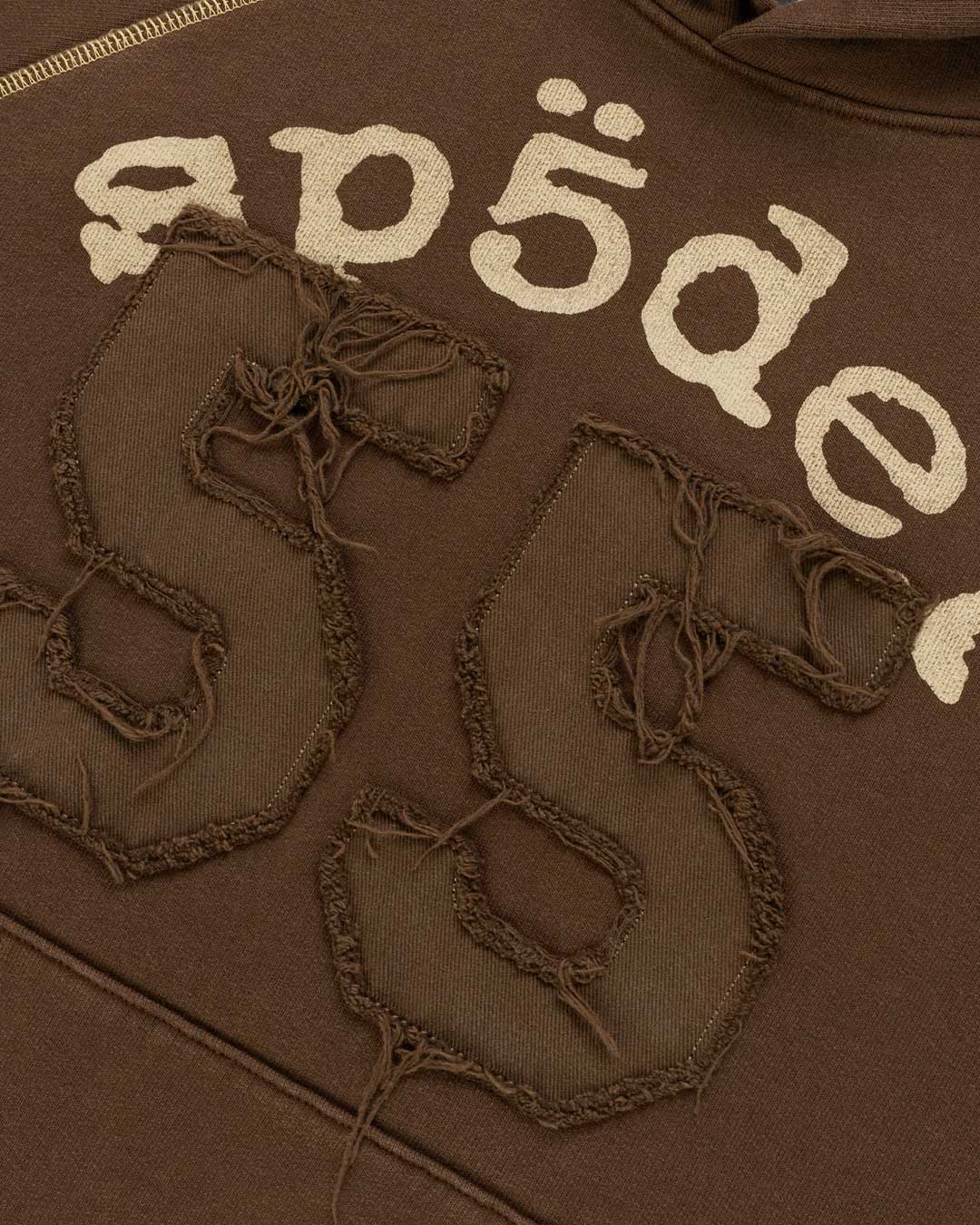 Sp5der 55 University Hoodie brown, close-up of the cream Sp5der lettering and distressed tonal 55 appliqué