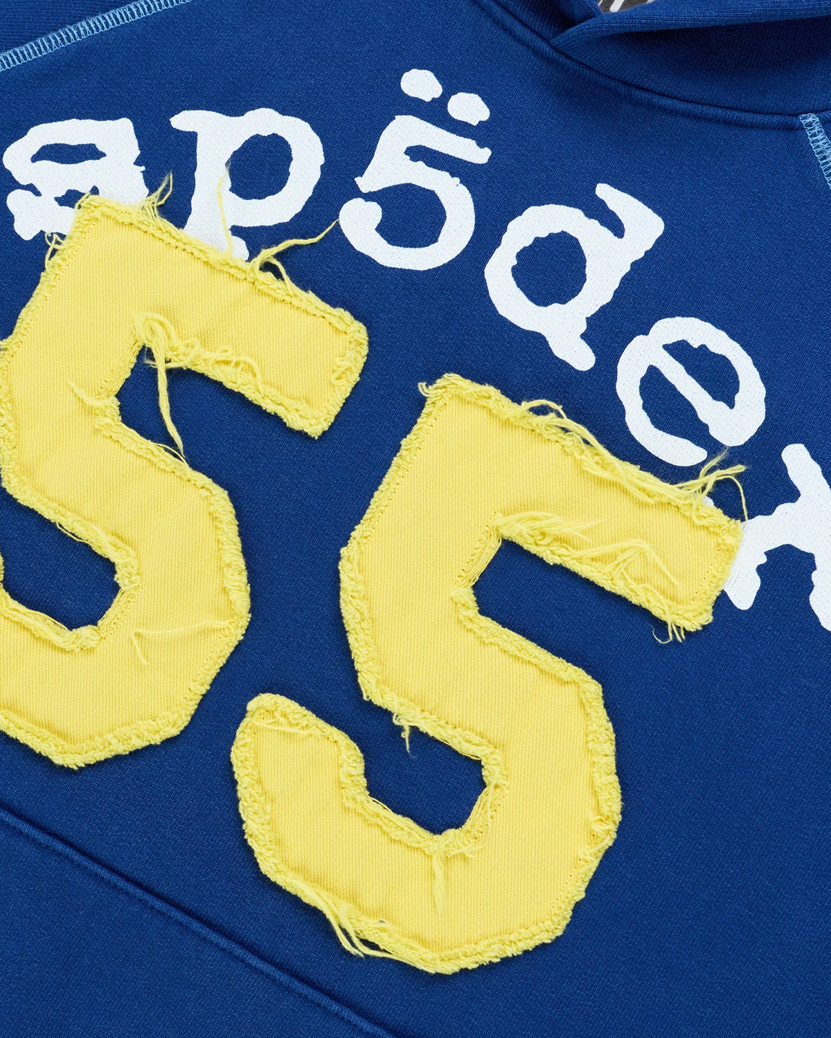 Sp5der 55 University Hoodie navy, close-up of the white Sp5der lettering and distressed yellow 55 appliqué