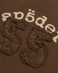 Sp5der 55 University Wide Leg Sweatpants brown, close-up of the Sp5der lettering and distressed 55 appliqué