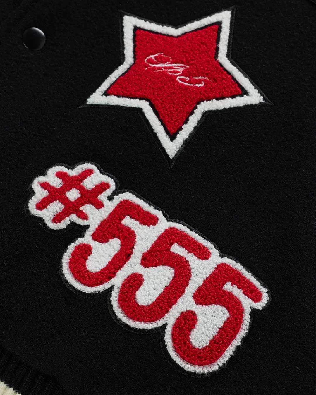 Sp5der District Cuntry Varsity Jacket black, close-up of the red star and #555 chenille patches