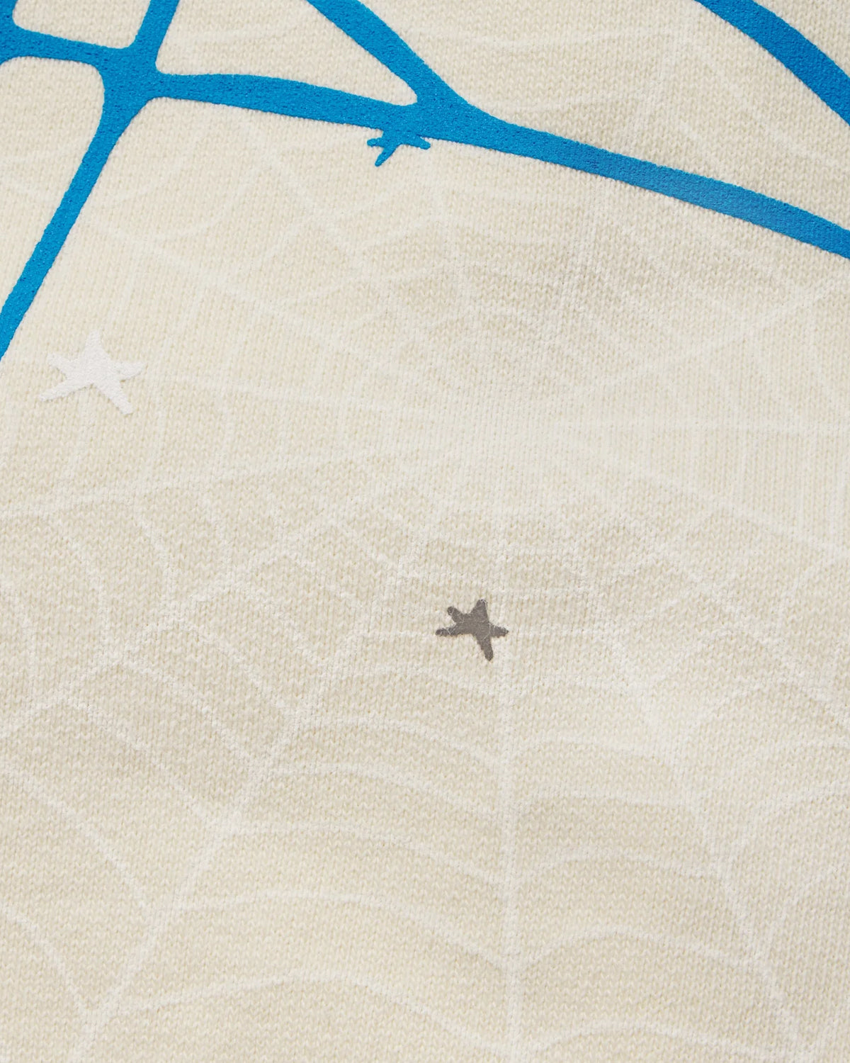 Sp5der Heavy Web Sweatpants foam cream, close-up of the tonal web print with a small star