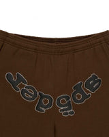 Sp5der OG Web Rhinestone Sweatpants brown, close-up of the full arched rhinestone wordmark below the elastic waistband