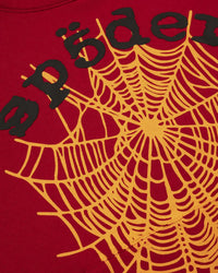 Sp5der OG Web V2 Hoodie red, close-up of the black spöder wordmark and orange spiderweb print